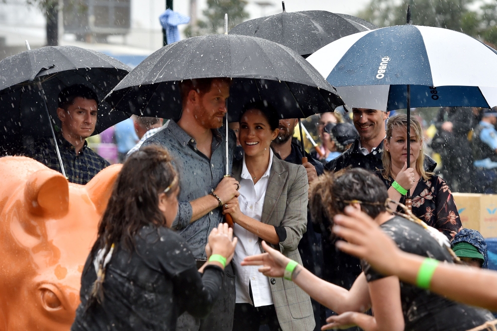 Britain's Prince Harry and his wife Meghan, Duchess of Sussex watch aboriginal dances at Victoria Park in Dubbo on October 17, 2018. / AFP / Pool / PETER PARKS
