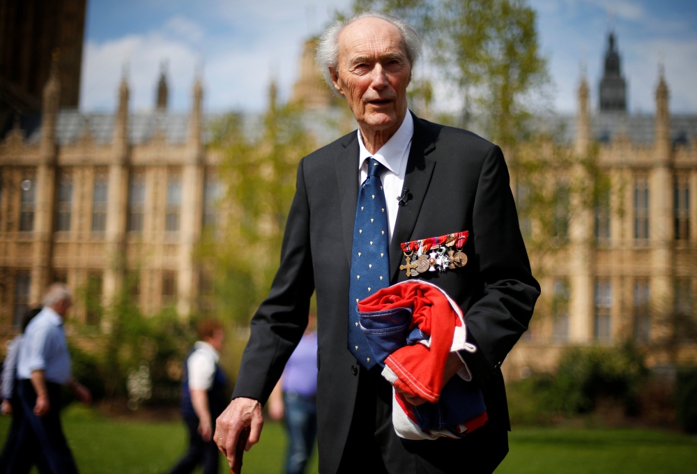 FILE PHOTO: World War Two Norwegian resistance fighter Joachim Roenneberg holds up a Union flag, which had been lowered from above the House of Lords, after it was presented to him by the Clerk of the House of Lords in Westminster, London, April 25, 2013.