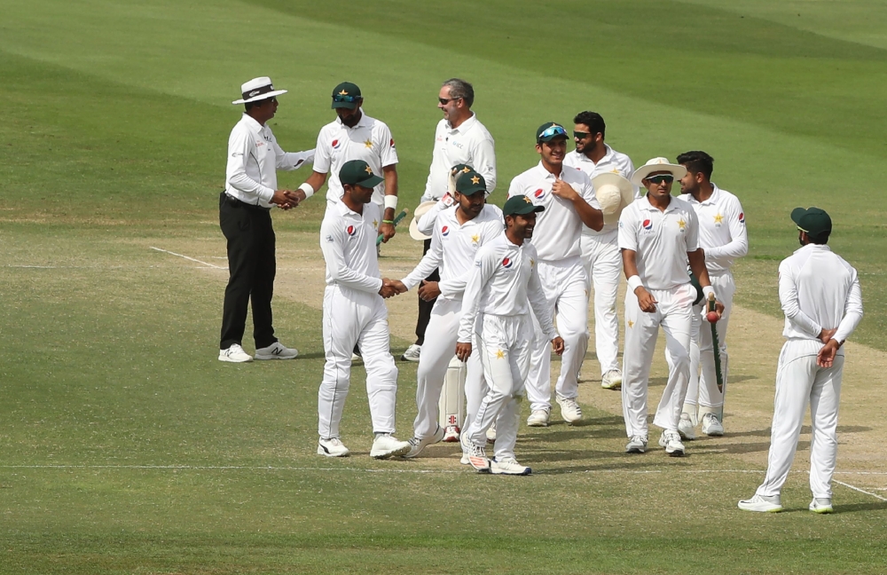 Pakistan cricketers celebrate at the end of day four of the second Test cricket match between Australia and Pakistan at Sheikh Zayed stadium in Abu Dhabi on October 19, 2018. (AFP / KARIM SAHIB)
