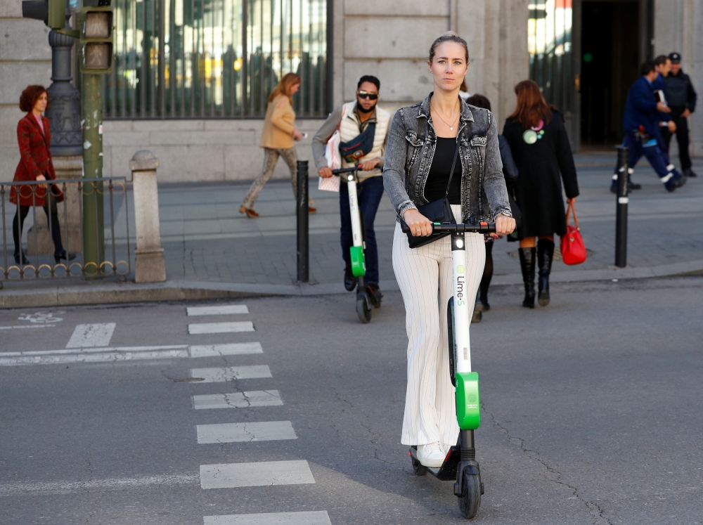 People ride dock-free electric scooters Lime-S by California-based bicycle and scooter sharing service Lime, over a crosswalk in Madrid, Spain, October 24, 2018. REUTERS/Paul Hanna