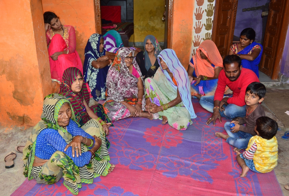 The Indian father (3rd R, in red) of a young boy who was killed by a macaques monkey sits with relatives at their family home in Agra on November 15, 2018.  AFP / Pawan Sharma