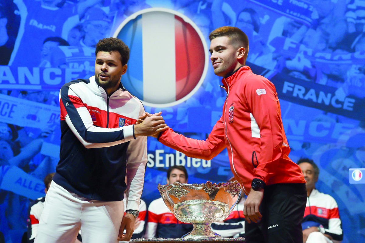 France's Jo-Wilfried Tsonga (L) and Croatia's Borna Coric shake hands next to the Davis Cup trophy on the eve of the Davis Cup tennis final between France and Croatia at the Pierre Mauroy Stadium in Villeneuve-d'Ascq, northern France, on November 22, 2018