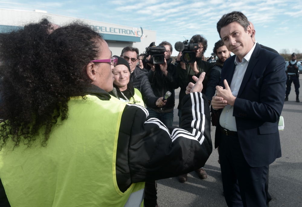 French Government's spokesperson Benjamin Griveaux (R) speaks with yellow vests (gilets jaunes) protestors before an official visit of Copelectronic, a company specialised in electronic and electric components, in Mouguerre, southwestern France, on Novemb