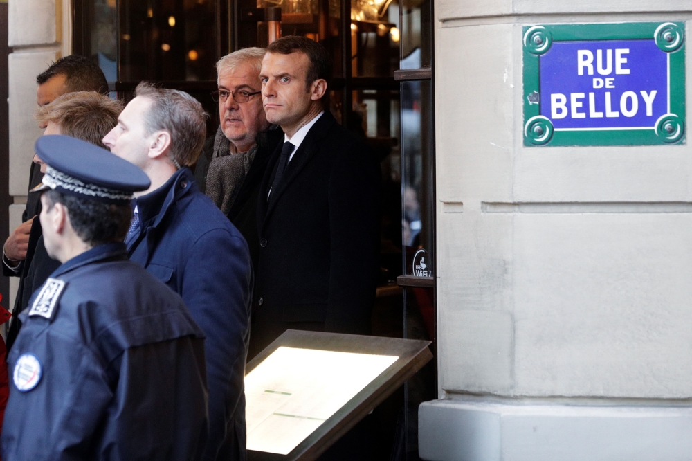 French President Emmanuel Macron (L) looks on at Cafe Belloy, near the Arc de Triomphe in Paris on December 2, 2018, a day after clashes during a protest of Yellow vests (Gilets jaunes) against rising oil prices and living costs.   AFP / Geoffroy VAN DER 