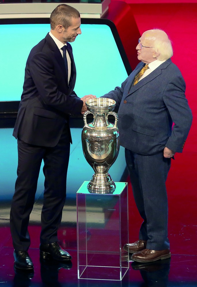 UEFA President Slovenian Aleksander Ceferin (L) shakes hands over the European Championship Trophy (C) with Irish President Michael D Higgins (R) during the UEFA Euro 2020 football competition qualifying draw in Dublin on December 2, 2018. AFP / Paul Fait