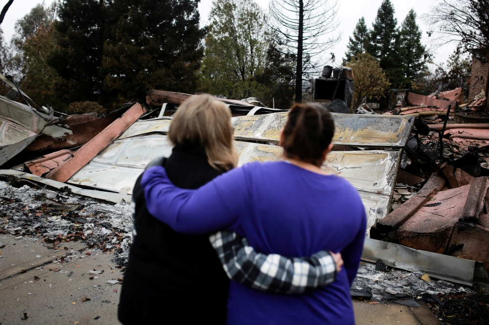 File photo of Irma Corona (R) comforts neighbor Gerryann Wulbern in front of the remains of Wulbern's home after the two returned for the first time since the Camp Fire in Paradise, California, U.S. November 22, 2018. REUTERS/Elijah Nouvelage