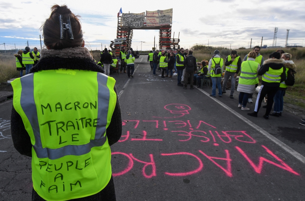 A Yellow vests (Gilets jaunes) protester with the words written of the back of her vest that read, ' Macron (referring to the French President) traitor, the people are hungry' blocks the road leading to the Frontignan oil depot in the south of France, as 
