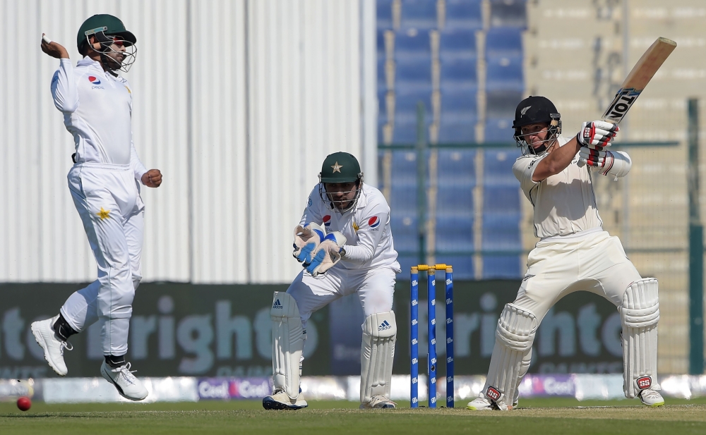 New Zealand batsman BJ Watling (R) plays a shot as Pakistani wicketkeeper captain Sarfraz Ahmed (C) looks on during the second day of the third and final Test cricket match between Pakistan and New Zealand at the Sheikh Zayed International Cricket Stadium