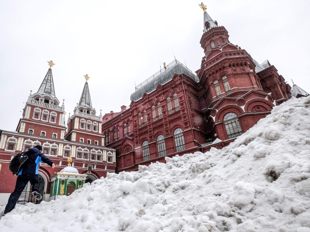A man makes his way through a snow heap towards Red Square after a night of heavy snowfall in Moscow on December 6, 2018. AFP / Yuri Kadobnov 