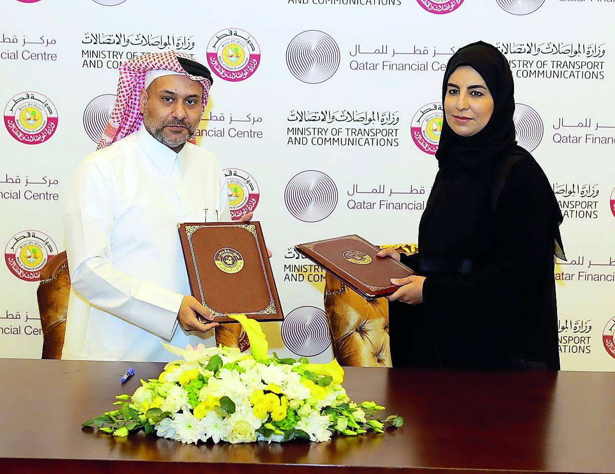 Reem Al Mansoori and Yousuf Mohamed Al Jaida exchanging documents during the signing ceremony.