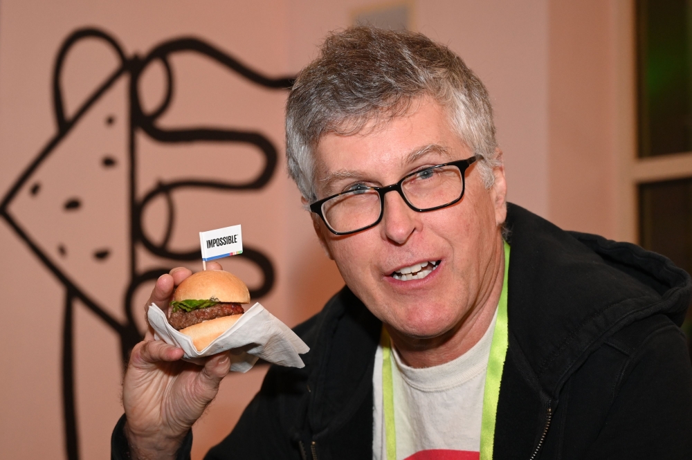 Impossible Foods CEO Pat Brown holds up an Impossible Burger 2.0, the new and improved version of the company's plant-based vegan burger that tastes like real beef, at a press event during CES 2019 in Las Vegas, Nevada on January 7, 2019.  AFP / Robyn Bec