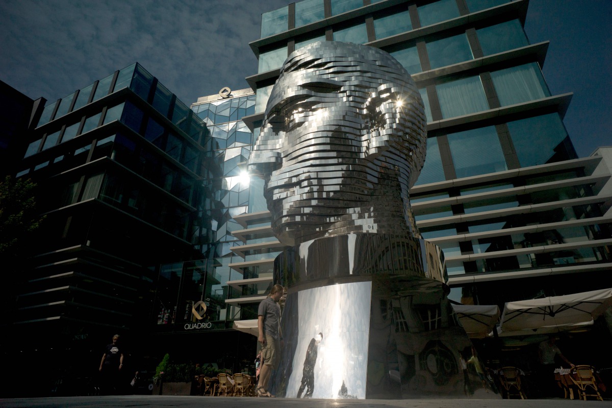 A pedestrian walks past the statue of a giant rotating head of writer Franz Kafka by Czech artist David Cerny on July 26, 2016 in Prague. AFP/Michal Cizek