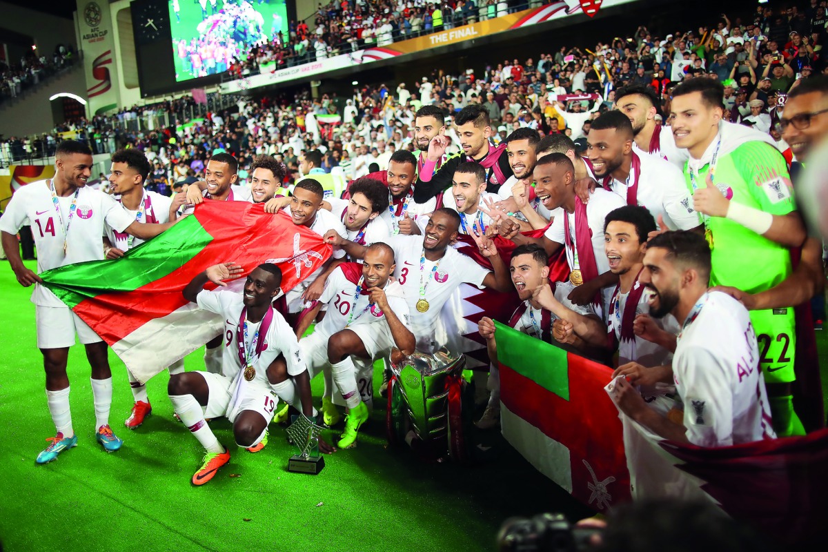 Qatar’s players celebrate with the trophy and Omani flag after winning the 2019 AFC Asian Cup final against Japan, in Abu Dhabi, yesterday.