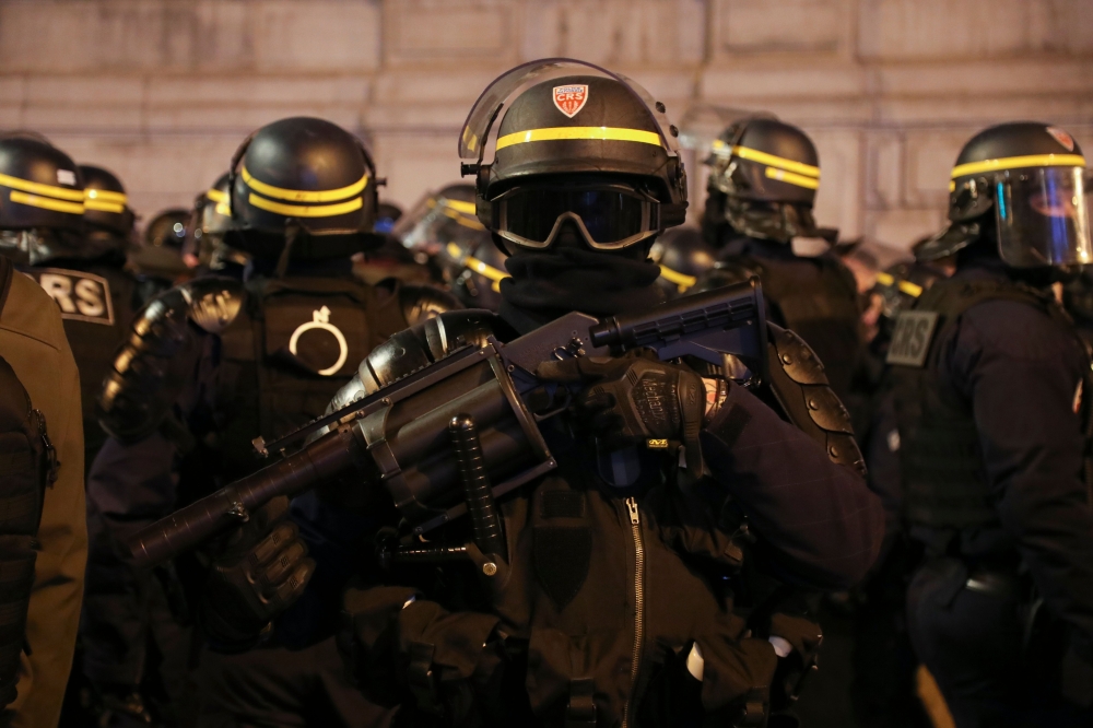 A riot police officer stands with a tear gas launcher during a demonstration in Paris on February 9, 2019 as the 