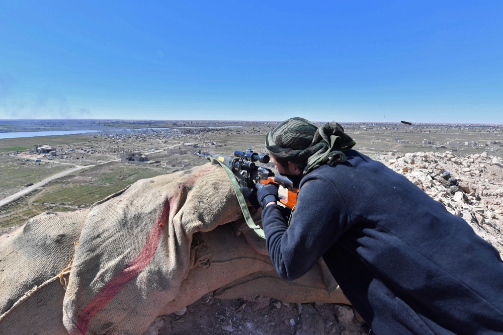 A sniper with the Syrian Democratic Forces (SDF) opens fire toward a part of Baghouz where remaining Islamic State (IS) group fighters are holding out in their last position, in the countryside of the eastern Syrian province of Deir Ezzor on March 18, 201