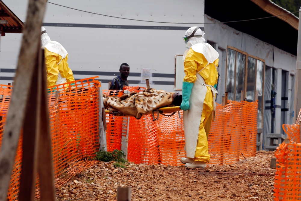 Health workers carry a newly admitted confirmed Ebola patient into the Red zone of the Ebola treatment centre in the Eastern Congolese town of Butembo in the Democratic Republic of Congo, March 28, 2019.  REUTERS/Baz Ratner