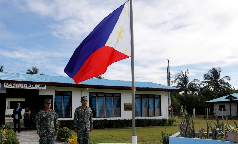 FILE PHOTO: Filipino soldiers stand at attention near a Philippine flag at Thitu island in disputed South China Sea April 21, 2017. REUTERS/Erik De Castro