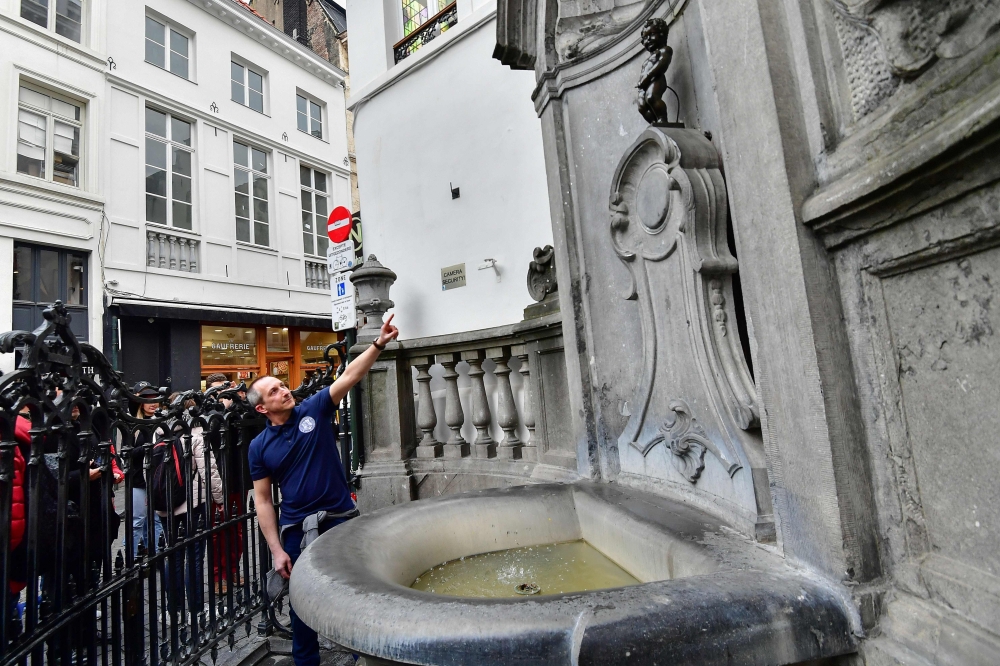 Brussels' energy technician Regis Callens points at the Manneken-pis landmark statue in Brussels on April 2, 2019.  AFP/Emmanuel Dunand 
 