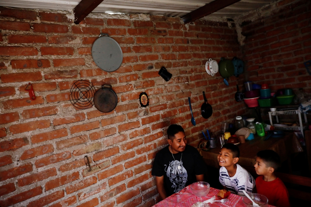 Arturo, 33, a Mexican migrant, who was denied a visa to the United States, smiles next his sons Juan , 10 and Javen, 6, as they eat breakfast inside their house in Neutla, Guanajuato state, Mexico, April 9, 2019. Picture taken April 9, 2019. Reuters/Edgar
