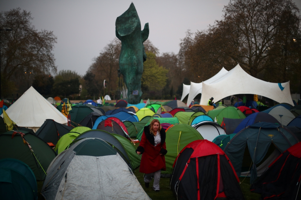 A climate change activist walks between tents during an Extinction Rebellion protest at Marble Arch in London, Britain April 16, 2019. REUTERS/Hannah McKay