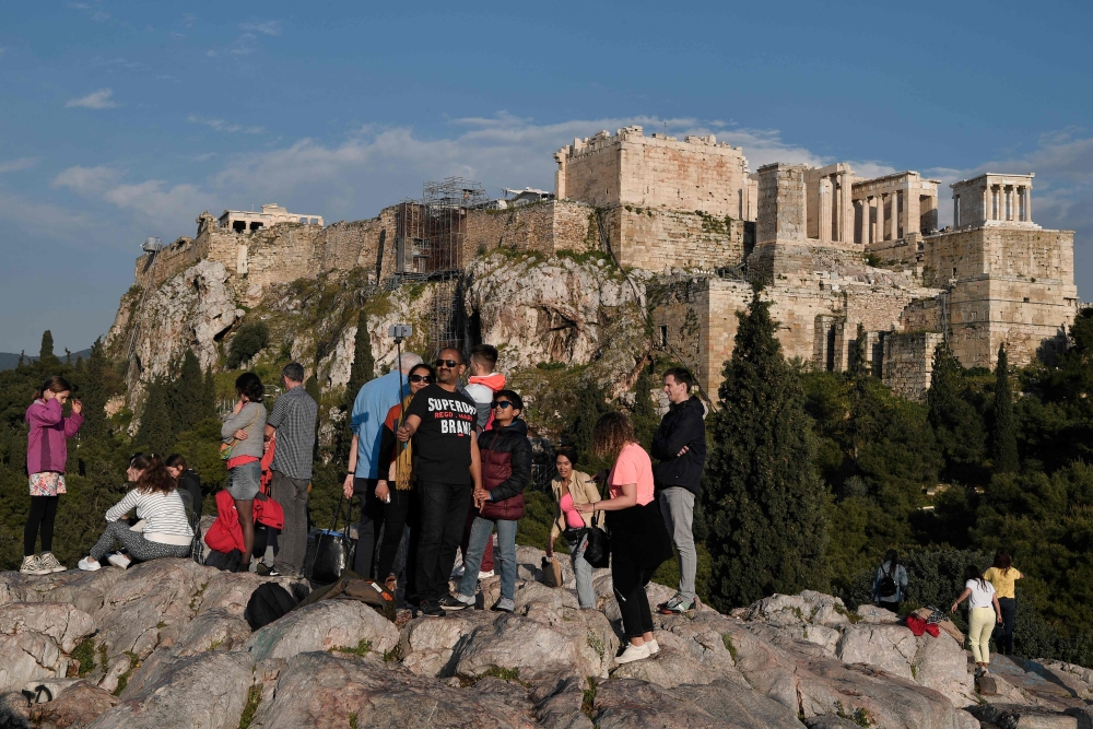 Tourists take selfies in front of the ancient Acropolis after it was closed following a lightning storm injuring four people on April 17, 2019.   AFP / LOUISA GOULIAMAKI
