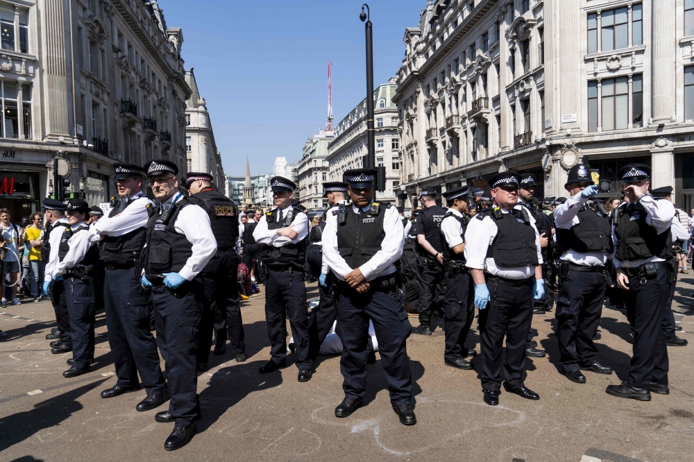 Police officers keep watch as climate change activists continue to block the road at Oxford Circus in London on April 20, 2019, on the sixth day of an environmental protest by the Extinction Rebellion group after police towed away the pink boat being used