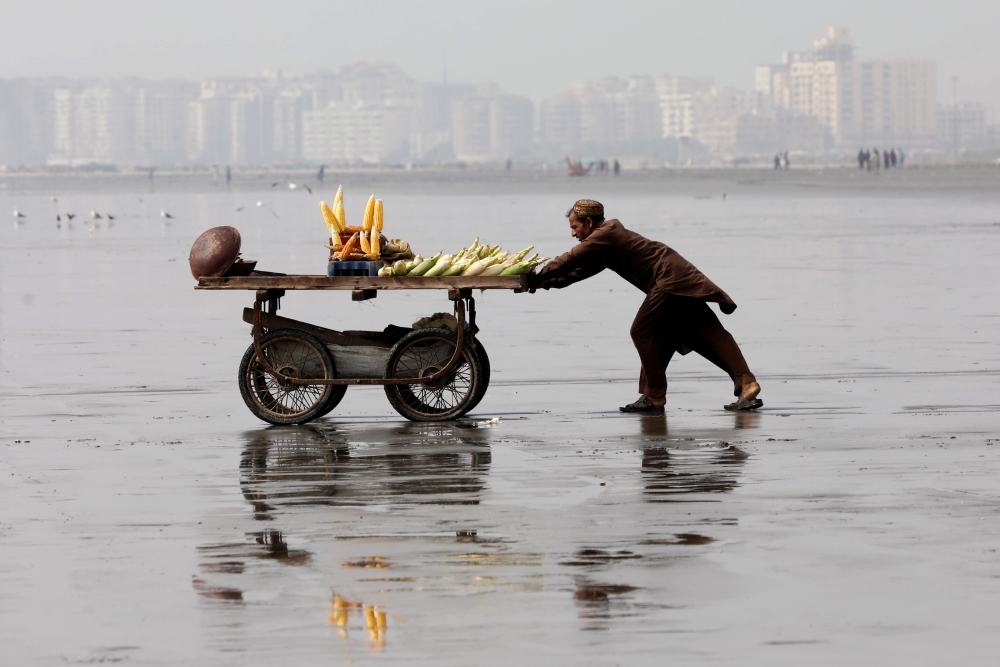 A man pushes a cart as he sells cooked corn on Clifton beach in Karachi, Pakistan, February 20, 2019. Reuters/Akhtar Soomro