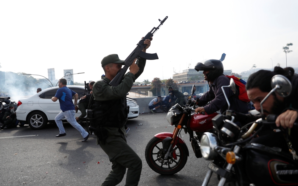 Soldiers and people react to the sound of gunfire near the Generalisimo Francisco de Miranda Airbase 