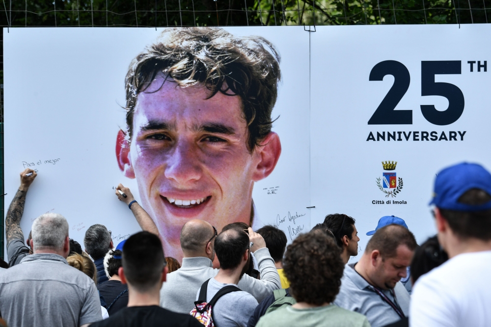 People sign a giant placard bearing a portrait of Brazilian's F1 driver Ayrton Senna on the 