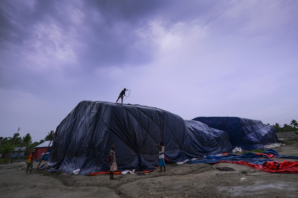  Bangladeshi workers cover a pile of fertiliser with a plastic sheet in Khulna on May 3, 2019, as Cyclone Fani barrels northeastwards into West Bengal state and towards Bangladesh. AFP / MUNIR UZ ZAMAN