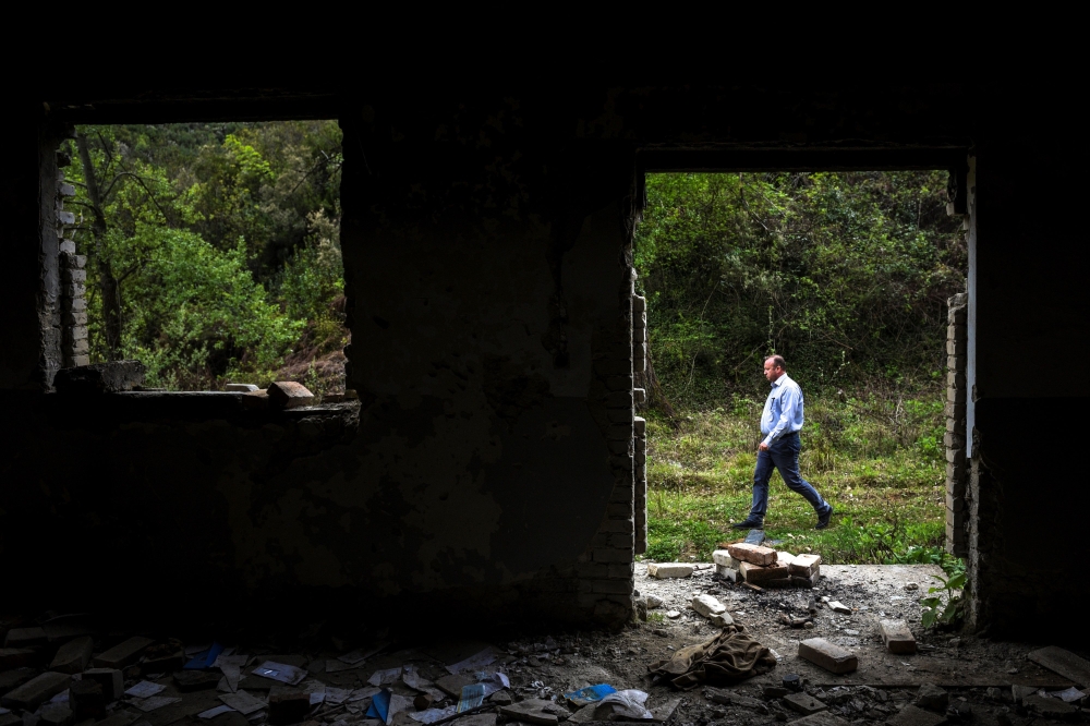 Jovan Plaku, 45, walks on April 22, 2019 on a former military base in the Dajti mountain near Tirana, where he believes his father was buried after he was killed by the communism regime on June 1977.  AFP / Gent Shkullaku 