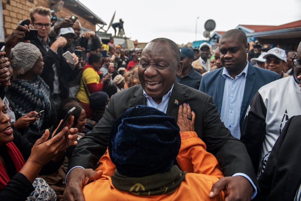 President of South Africa and the African National Congress Cyril Ramaphosa (C) greets a voter as he arrives to cast his vote for the general elections at the Hitekani Primary School, Chiawelo, Soweto, on May 8, 2019. AFP / Michele Spatari