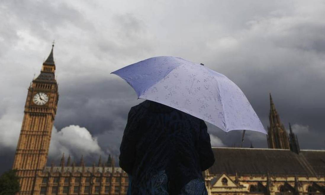 A woman looks towards dark clouds over the Houses of Parliament in central London August 11, 2014. Reuters/Luke MacGregor 