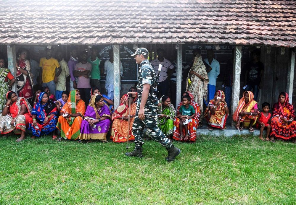 Indian voters sit as they queue to cast their vote as paramilitary personnel stand guard in the Ghoramara island around 110 km south of Kolkata on May 19, 2019, during the 7th and final phase of India's general election. AFP / DIBYANGSHU SARKAR