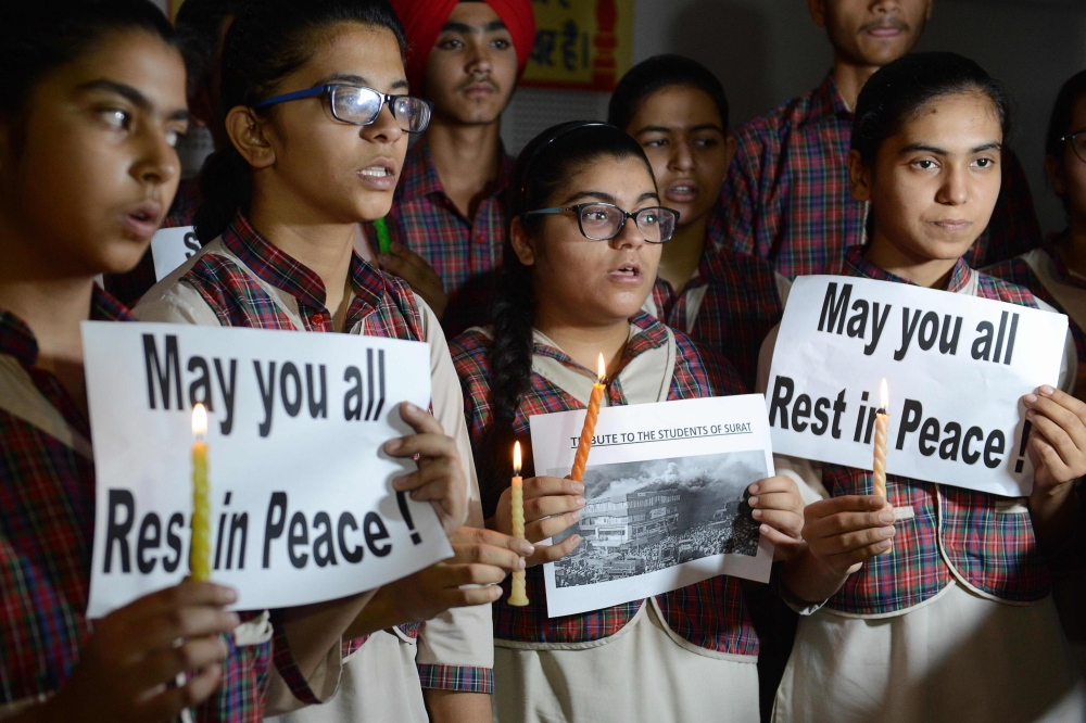 Indian students hold candles as they pay tribute to the students died in a fire in a building in India housing a college in Surat, at a school in Amritsar on May 25, 2019. AFP / NARINDER NANU