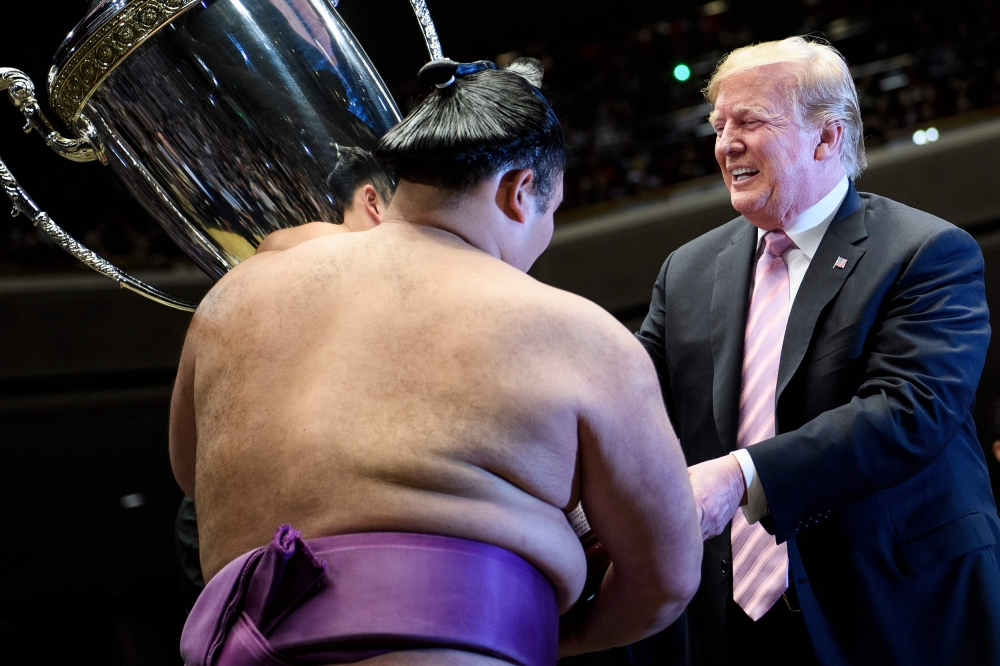 US President Donald Trump presents the President's Cup to sumo wrestler Asanoyama during the Summer Grand Sumo Tournament at Ryogoku Kokugikan Stadium in Tokyo on May 26, 2019. / AFP / Brendan Smialowski
