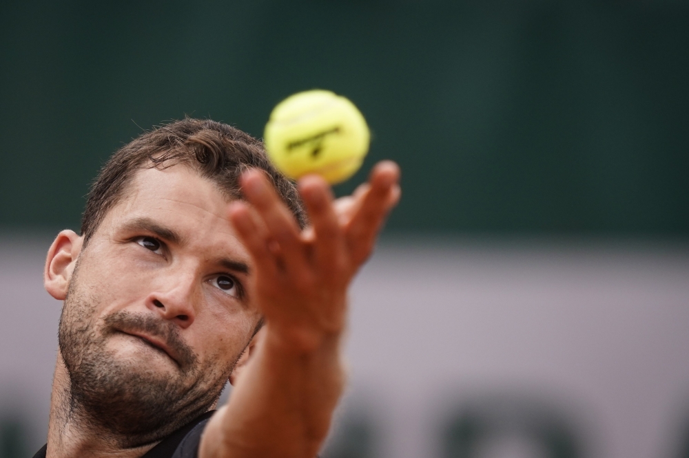 Bulgaria's Grigor Dimitrov serves to Serbia's Janko Tipsarevic during their men's singles first round match on day 1 of The Roland Garros 2019 French Open tennis tournament in Paris on May 26, 2019. / AFP / Kenzo TRIBOUILLARD