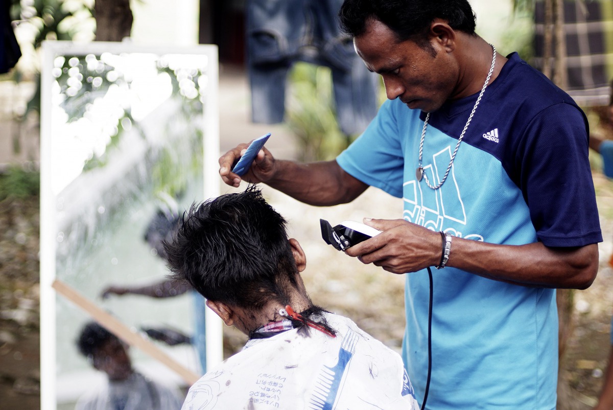 A Rohingya refugee cuts the hair of a kid at a temporary shelter in Beras Pati after having arrived from Aceh Shelter in Medan of North Sumatra, Indonesia on November 25, 2016. Jefri Tarigan/Anadolu Agency