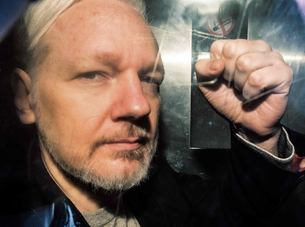 FILE PHOTO: WikiLeaks founder Julian Assange gestures from the window of a prison van as he is driven into Southwark Crown Court in London, before being sentenced to 50 weeks in prison for breaching his bail conditions in 2012.   AFP / Daniel LEAL-OLIVAS