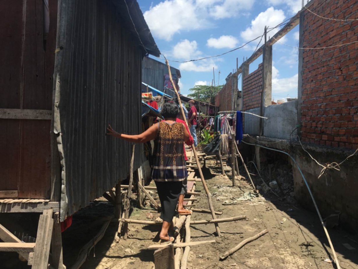 A woman walks on a makeshift bridge of wooden planks and poles in an informal settlement at the edge of Boeung Tompoun, Phnom Penh, Cambodia. May 27, 2019. Thomson Reuters Foundation/Rina Chandran