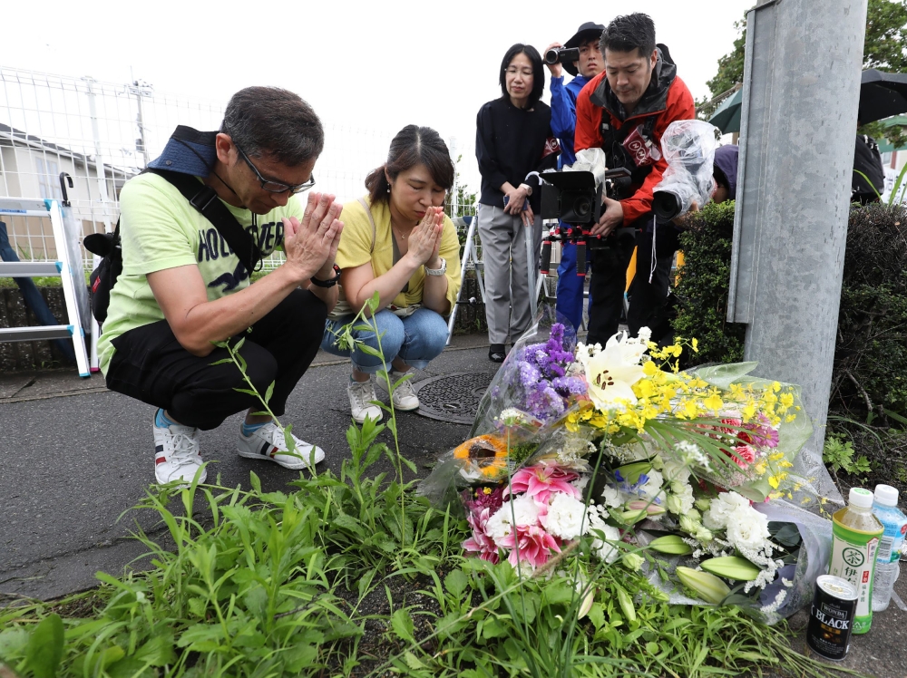 Residents pray for victims of a fire which hit the Kyoto Animation company studio the day before, killing 33 people, in Kyoto on July 19, 2019. (AFP / JIJI PRESS)