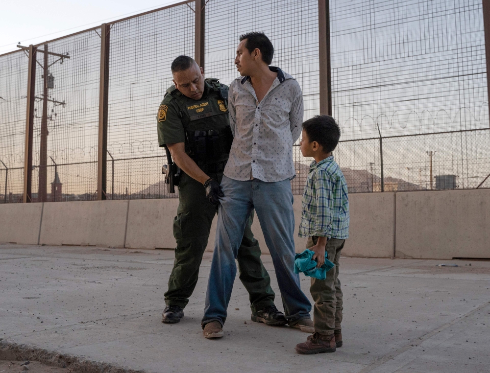 In this file photo taken on May 16, 2019, José, 27, with his son José Daniel, 6, is searched by US Customs and Border Protection Agent Frank Pino in El Paso, Texas. (AFP / Paul Ratje)