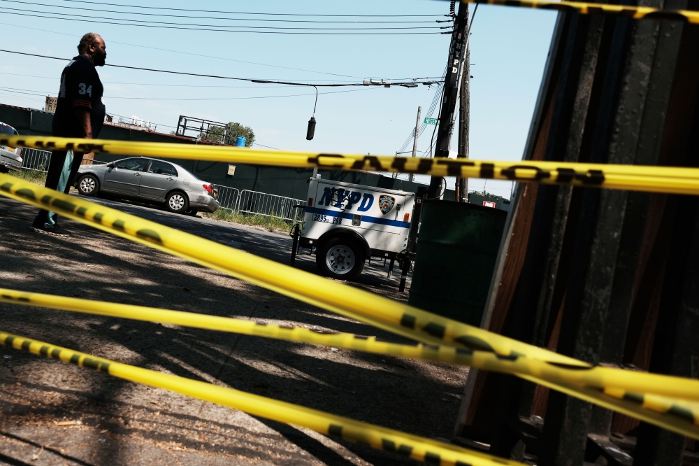 A man walks by police tape in the Brownsville neighborhood in Brooklyn where one person was shot and killed and 11 others were injured after two or more shooters opened fire during a massive block party on July 29, 2019 in New York City.  Spencer Platt/AF