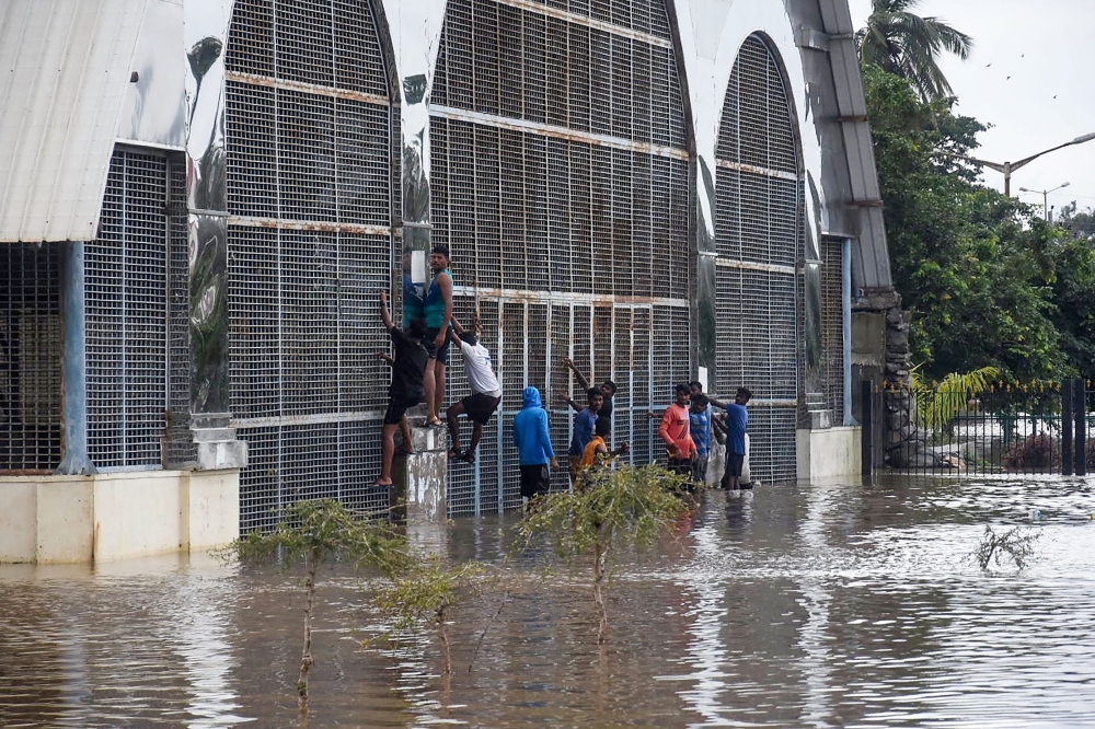 Youth climb up on the iron gates of a building submerged by floodwaters of the Kabini river at Nanjangudu in the Mysore district about 170 kms of the city of Bangalore on August 10, 2019.  AFP / STR