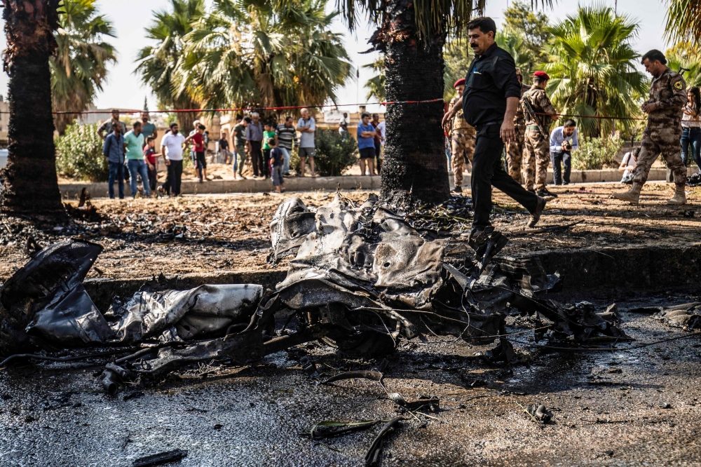 People and security forces gather at the scene of a car bomb explosion in the Kurdish-majority city of Qamishli in northeastern Syria's Hasakeh province on August 18, 2019.   AFP / Delil SOULEIMAN