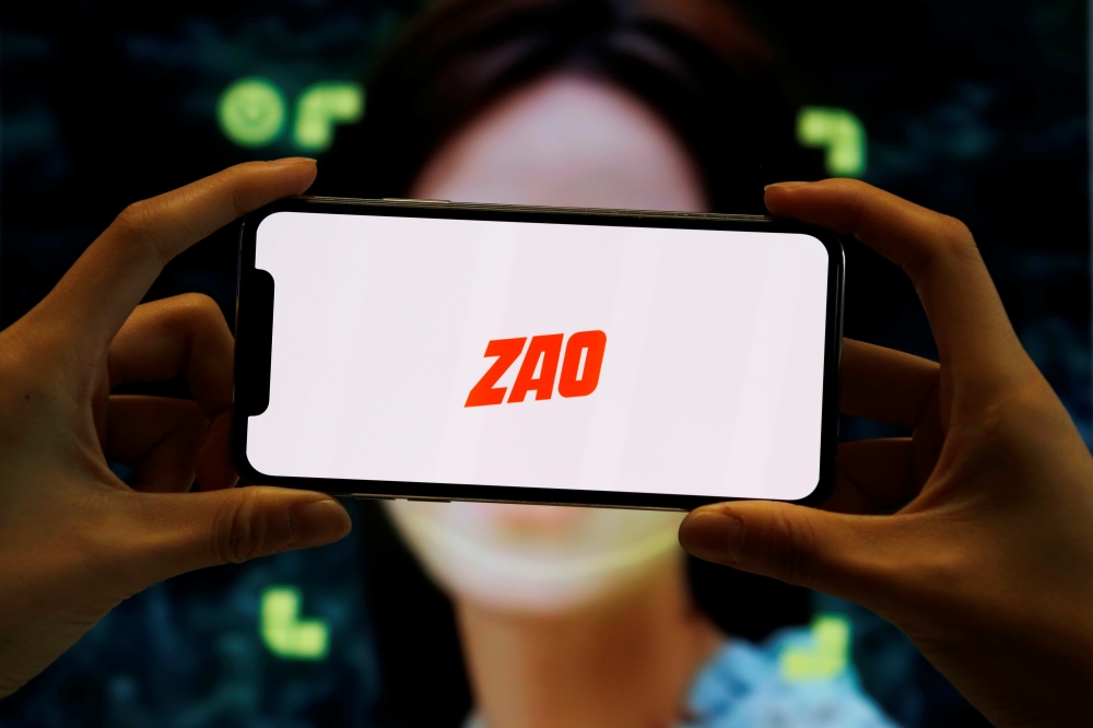 The logo of the Chinese app ZAO, which allows users to swap their faces with celebrities and anyone else, is seen on a mobile phone screen in front of an advertisement of the app, in this illustration picture taken September 2, 2019. REUTERS/Florence Lo/I