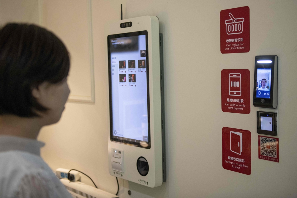In this picture taken on August 21, 2019, a woman uses a facial recognition device installed at an IFuree Go self-service supermarket in Tianjin. AFP / Nicolas Asfouri 