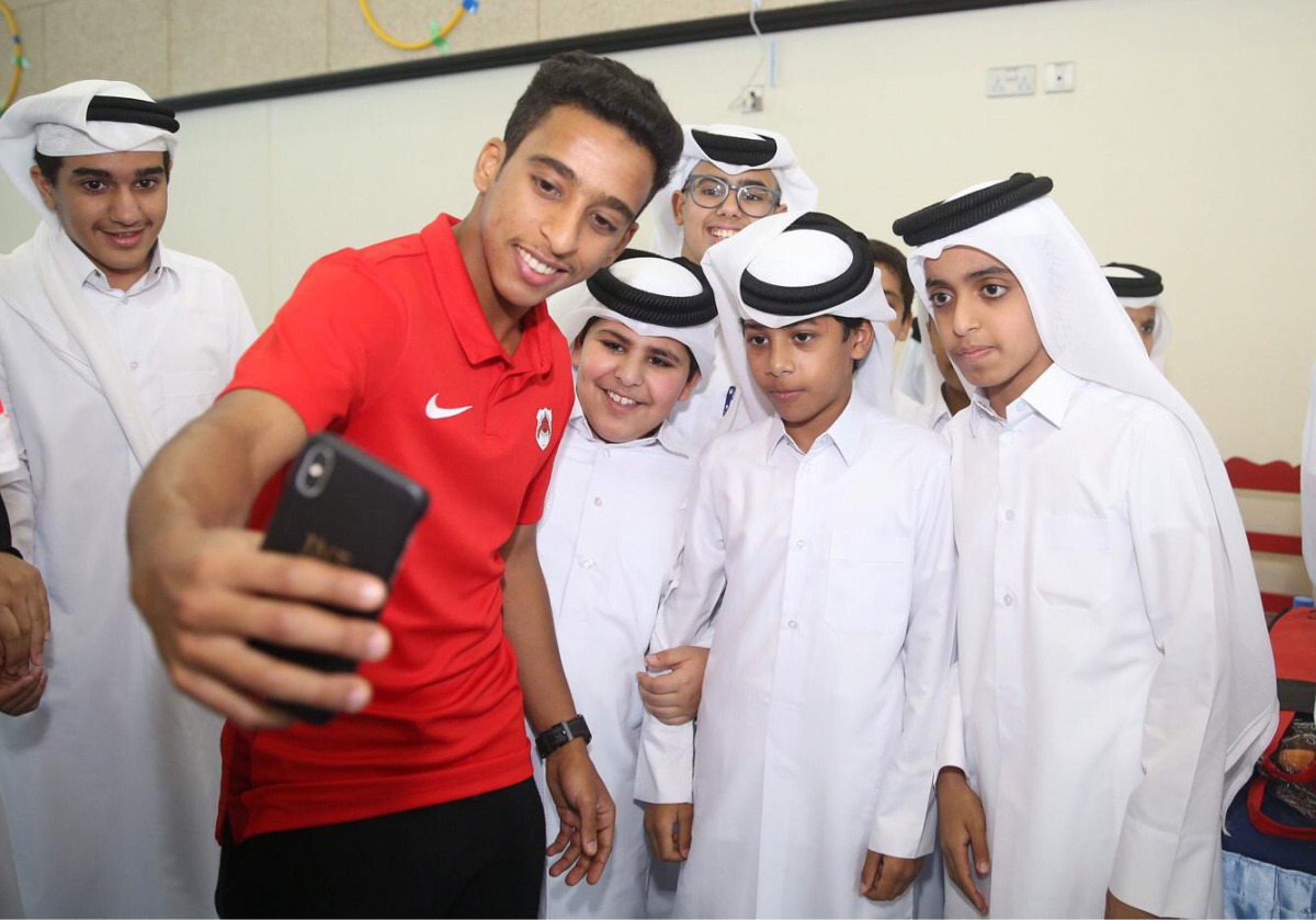 Al Rayyan’s midfielder Ahmed Al Saadi takes a selfie with schoolchildren during a promotional event.  