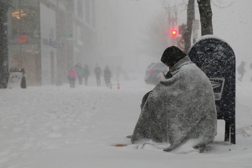A homeless man asks for money outside a donut shop during white-out blizzard-like conditions in a winter snow storm in Boston, February 9, 2017. Reuters/Brian Snyder