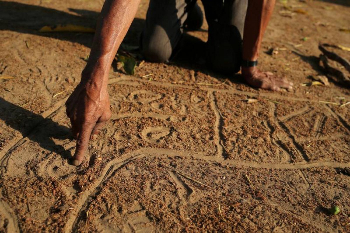 Manoel Kanunxi, chief of the Manoki indigenous people, points to the location of his people's land that was burnt, on a map drawn in dirt, on the outskirts of Brasnorte, in Mato Grosso state, Brazil August 27, 2019. Reuters/Amanda Perobelli